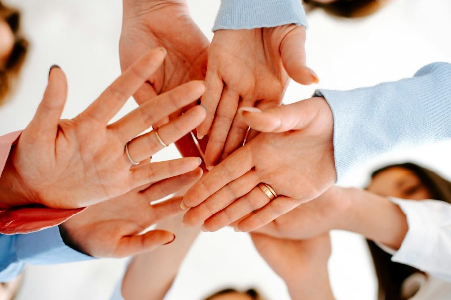 Mitglied werden Verschiedene Hände, die übereinander gelegt sind, symbolisieren Zusammenarbeit und Einheit.